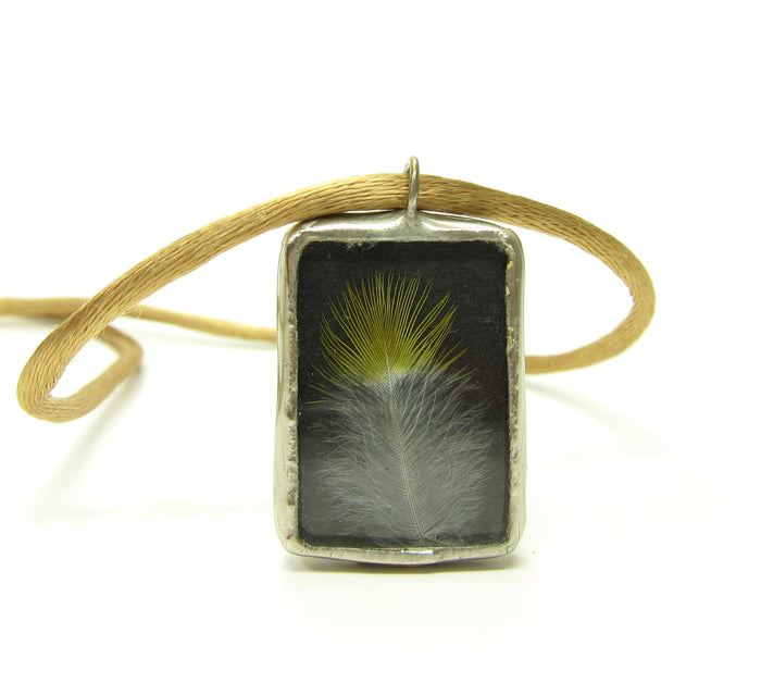 Made with found objects, this necklace includes a real bird feather and upcycled glass.