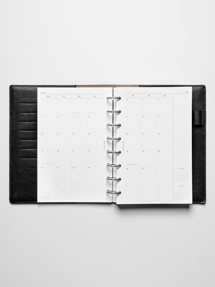 Image shows the Monday Start 2026 Dated Monthly Planner Inserts used in a black leather Half Letter disc-bound planner.